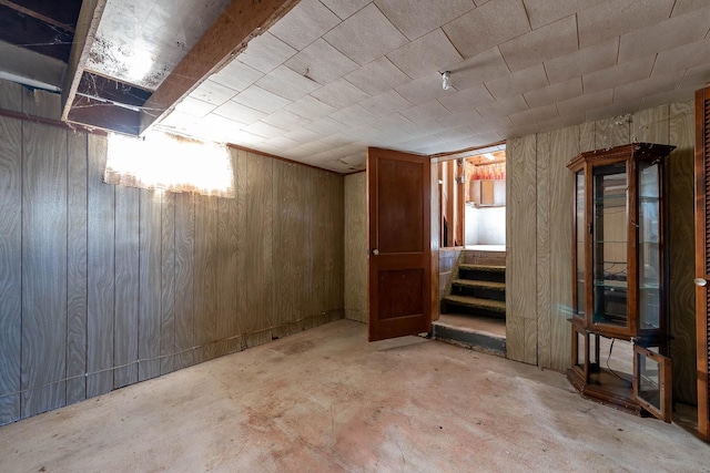 below grade area featuring a wealth of natural light, wooden walls, and stairway
