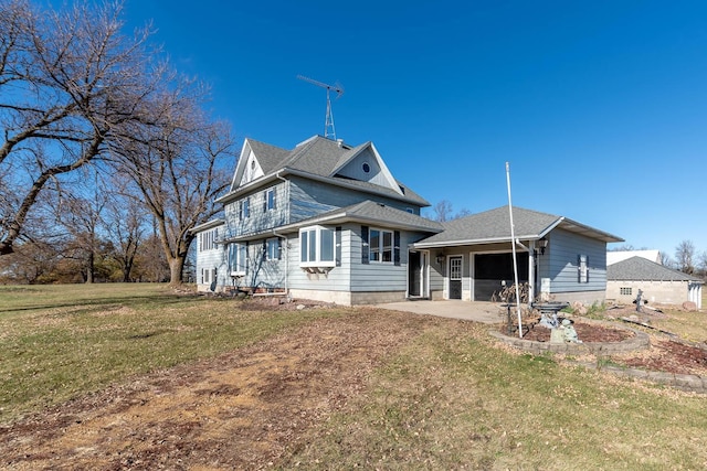 rear view of house with a lawn, a patio, and a garage