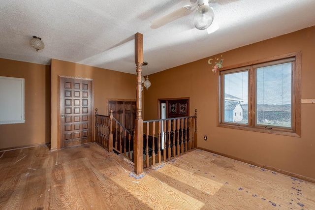 stairway with baseboards, a ceiling fan, a textured ceiling, and wood finished floors