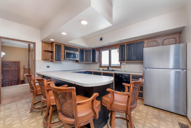 kitchen with a sink, light floors, black appliances, and blue cabinetry