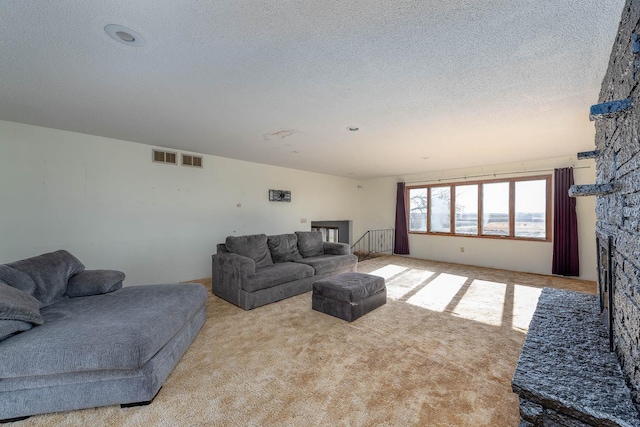 carpeted living area with a textured ceiling, visible vents, and a fireplace