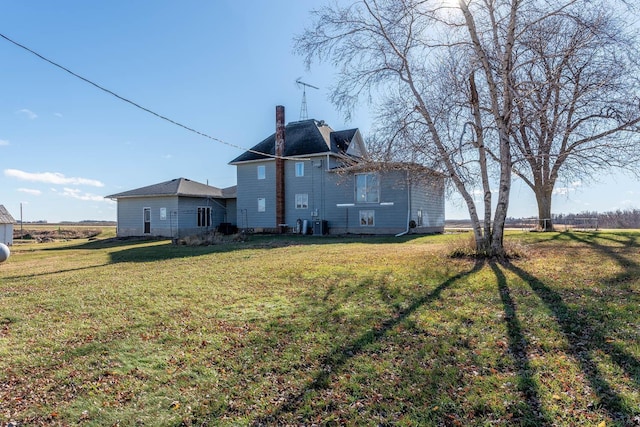 back of property featuring a chimney and a yard