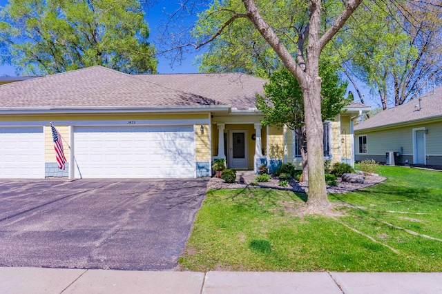 view of front facade with a garage, asphalt driveway, a front lawn, roof with shingles, and central air condition unit