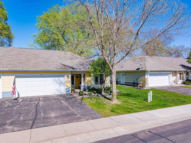 view of front of house with a garage, driveway, a front lawn, and roof with shingles