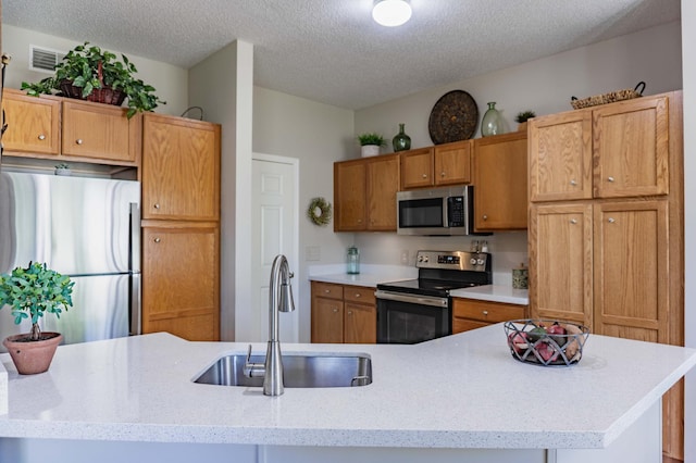 kitchen featuring appliances with stainless steel finishes, a sink, and a textured ceiling