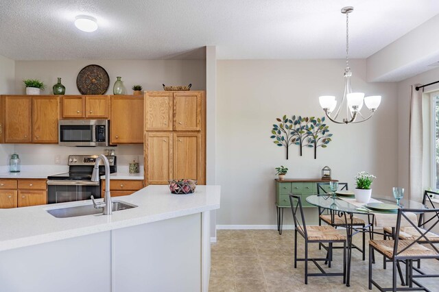 kitchen with stainless steel appliances, a sink, light countertops, a chandelier, and pendant lighting