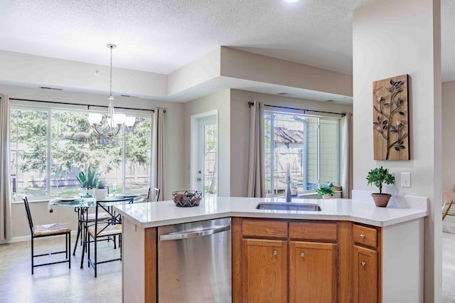 kitchen featuring stainless steel dishwasher, light countertops, brown cabinetry, a sink, and a textured ceiling