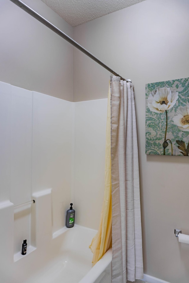 full bath featuring shower / bath combo with shower curtain and a textured ceiling