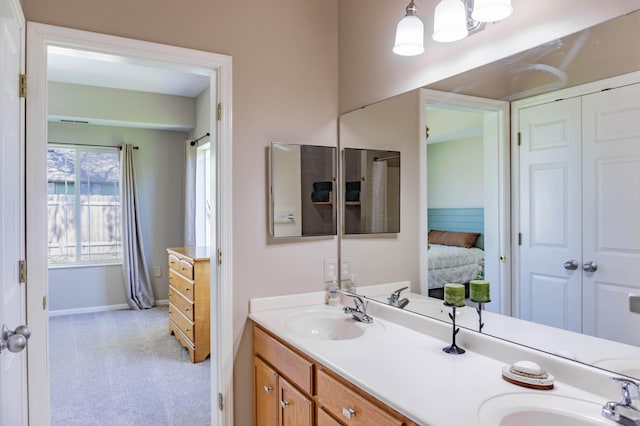 ensuite bathroom featuring baseboards and double vanity