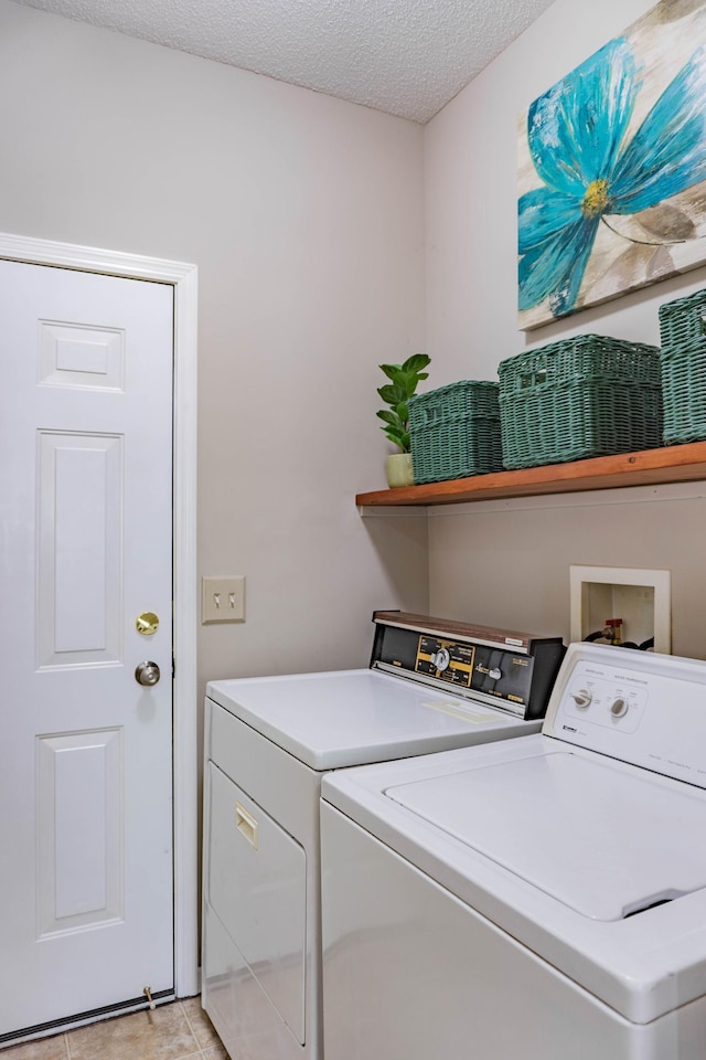 washroom with washing machine and dryer, a textured ceiling, and light tile patterned floors