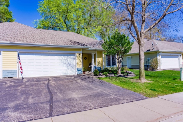 ranch-style home featuring an attached garage, asphalt driveway, and a front lawn