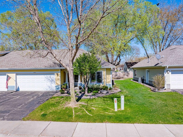 view of front of house featuring a front lawn, asphalt driveway, and an attached garage