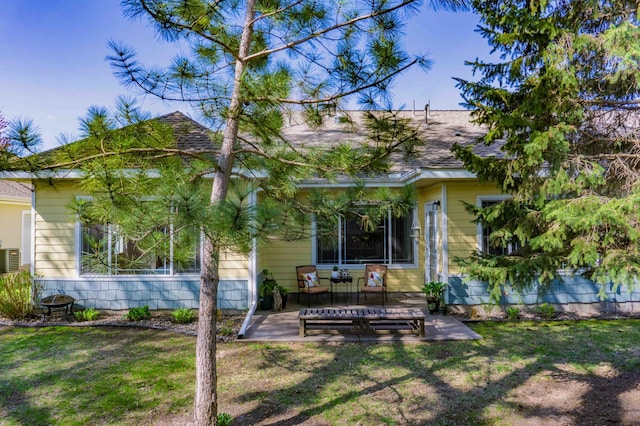 back of property featuring a yard, roof with shingles, and a patio