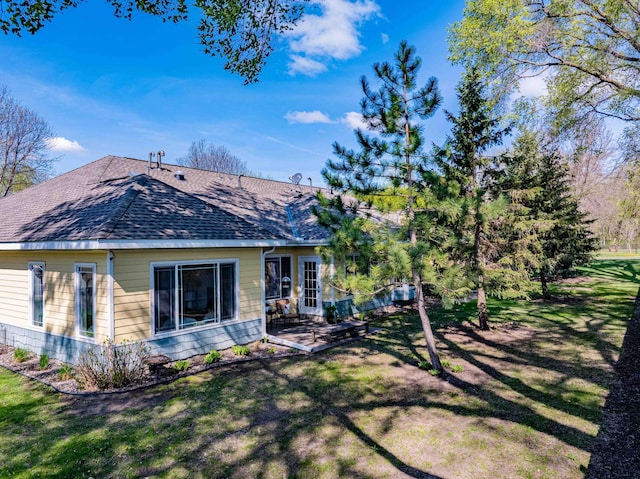 back of house featuring a shingled roof, a patio area, and a lawn