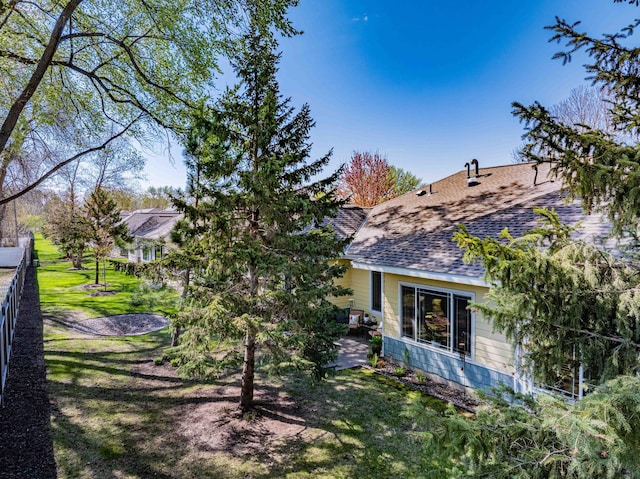 rear view of house with roof with shingles and a patio area