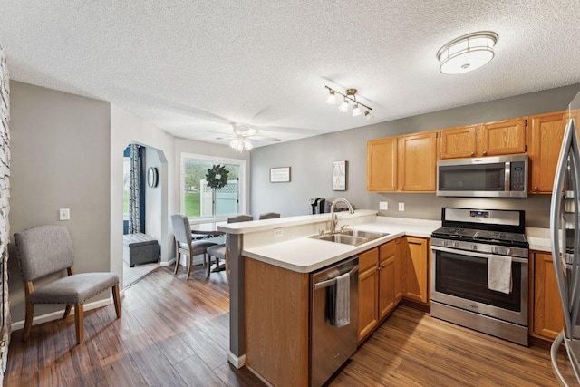1711 121st Ln NW, Coon Rapids, MN 55448 - kitchen with stainless steel appliances, a sink, a peninsula, a textured ceiling, and light countertops