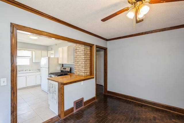 kitchen featuring stainless steel range with gas cooktop, butcher block counters, ceiling fan, white cabinetry, and a sink
