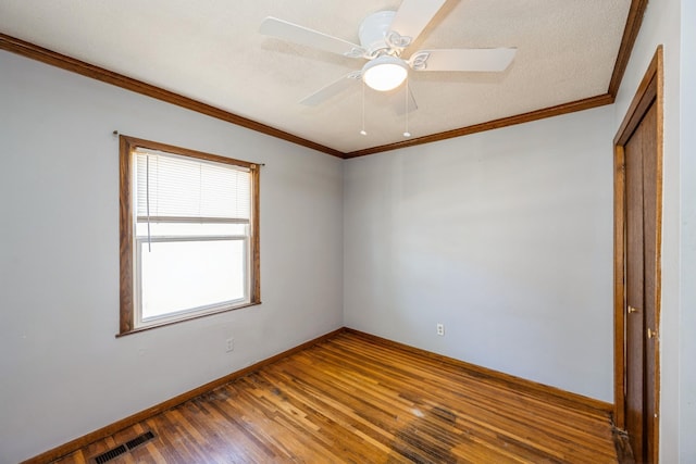 spare room with wood finished floors, ceiling fan, crown molding, and baseboards