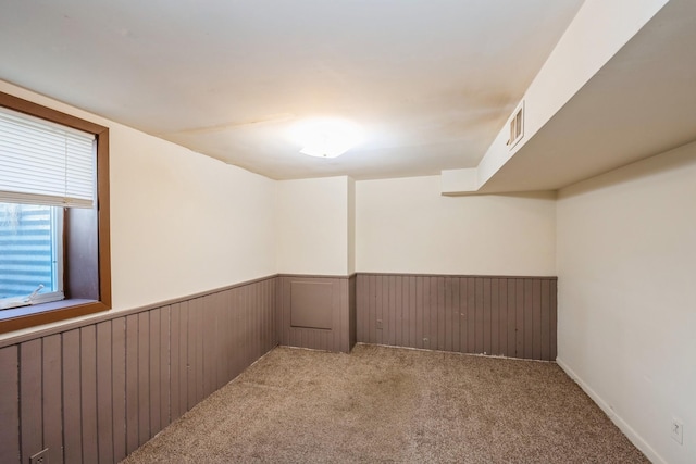 basement with a wainscoted wall, carpet, and wooden walls