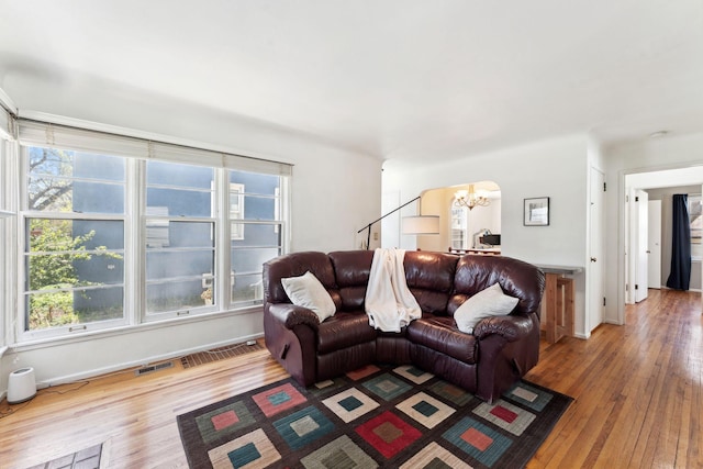 living room featuring baseboards, visible vents, hardwood / wood-style flooring, and a notable chandelier