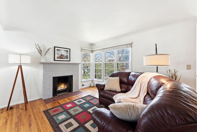 living area featuring a fireplace, baseboards, and light wood-type flooring