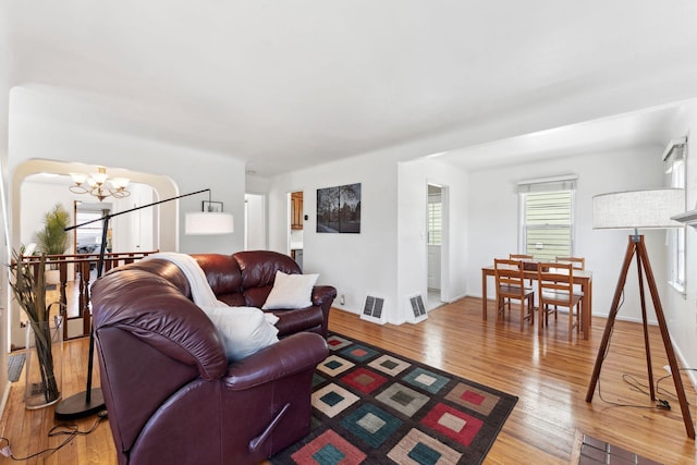 living area featuring an inviting chandelier, light wood-style floors, baseboards, and visible vents
