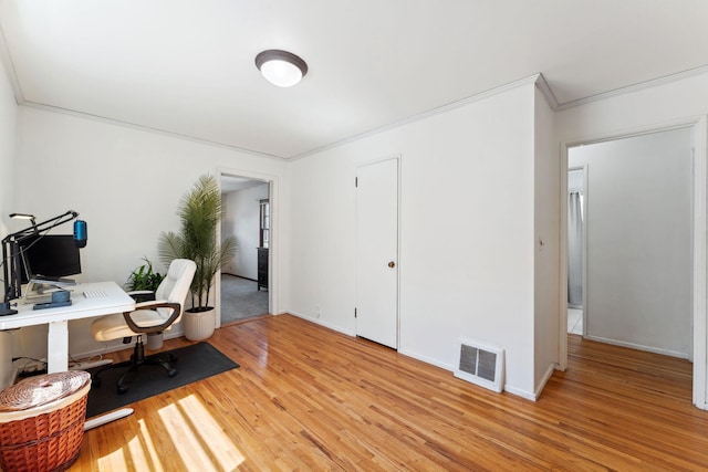 office area with light wood-style floors, baseboards, ornamental molding, and visible vents