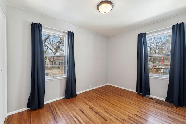 unfurnished room with baseboards, light wood-style flooring, and visible vents