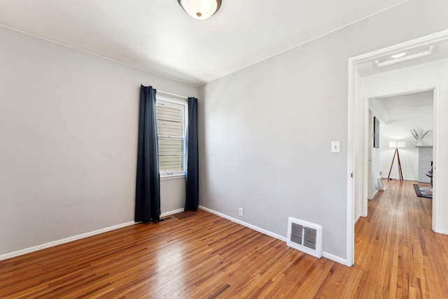 empty room featuring visible vents, light wood-style floors, and baseboards