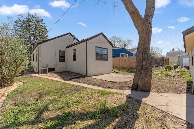 exterior space featuring fence, cooling unit, stucco siding, a patio area, and a lawn