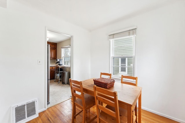 dining area featuring visible vents, light wood-style floors, and baseboards