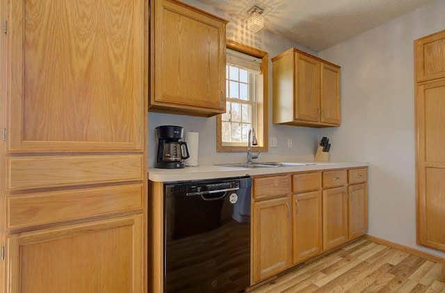 kitchen featuring light wood-style floors, baseboards, light countertops, a sink, and dishwasher