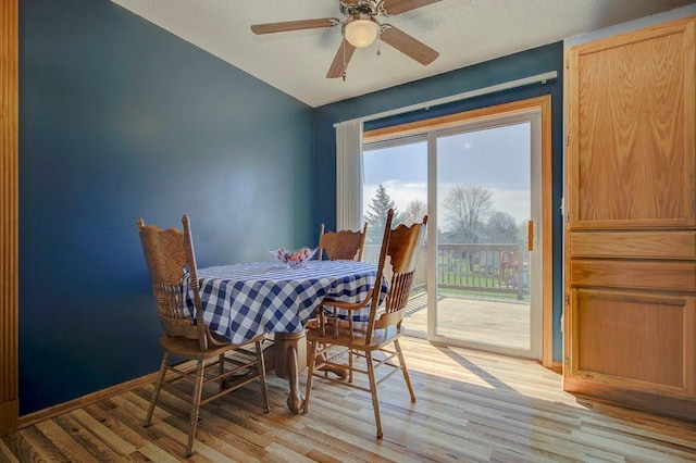 dining space with light wood-style floors, baseboards, ceiling fan, and lofted ceiling
