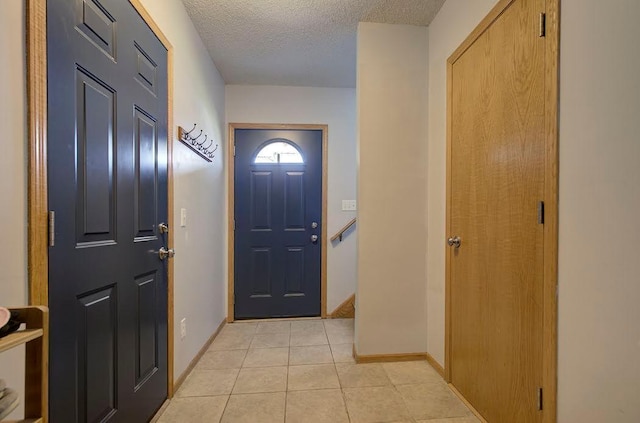 entrance foyer with baseboards, a textured ceiling, and light tile patterned flooring