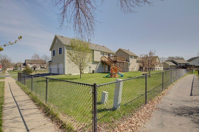 view of front of property featuring an attached garage, fence, a residential view, and a front yard