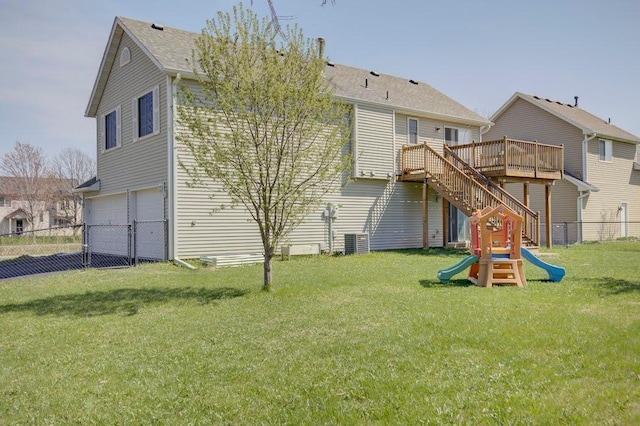 rear view of house with fence, an attached garage, a wooden deck, a playground, and a yard