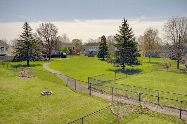 view of property's community with an outdoor fire pit, fence, and a yard