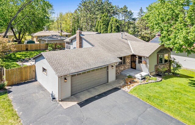 view of front of home featuring a shingled roof, asphalt driveway, a chimney, an attached garage, and stone siding