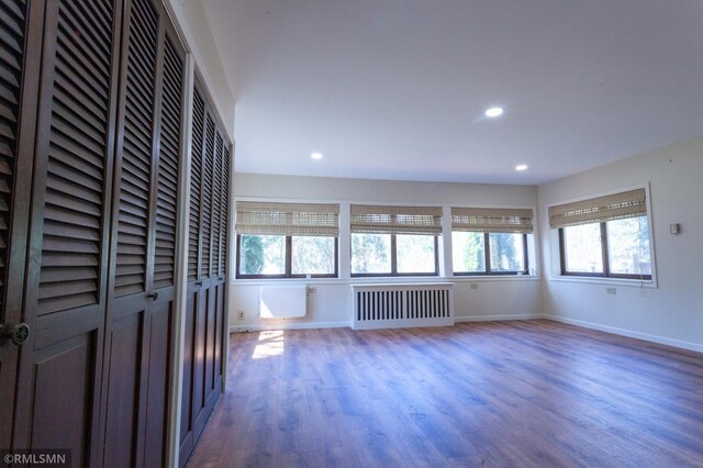 unfurnished living room featuring radiator heating unit, healthy amount of natural light, wood finished floors, and recessed lighting