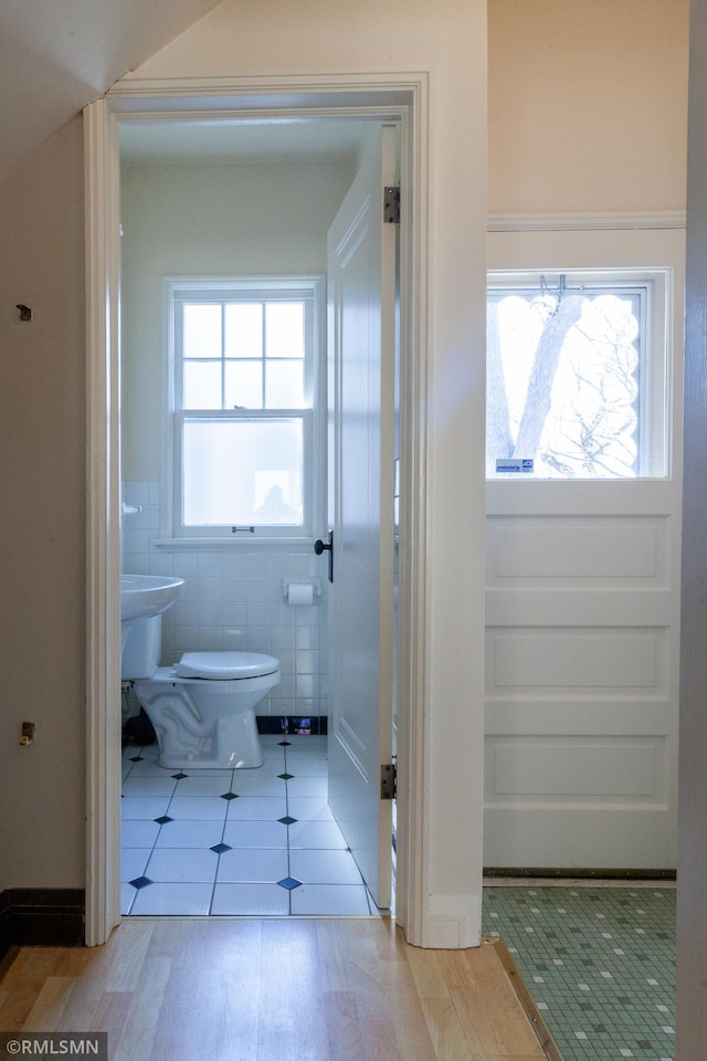 bathroom with toilet, tile walls, and wood finished floors