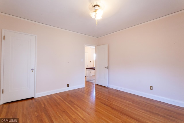 unfurnished room featuring light wood finished floors, baseboards, and crown molding
