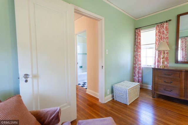 sitting room with wood finished floors, crown molding, and baseboards