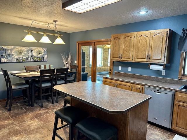 kitchen with dark countertops, dishwasher, a textured ceiling, a center island, and a kitchen bar