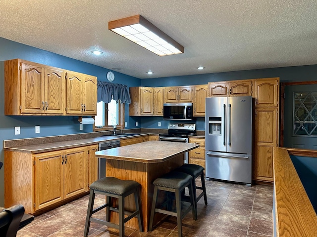 kitchen featuring a sink, a textured ceiling, a kitchen bar, and stainless steel appliances
