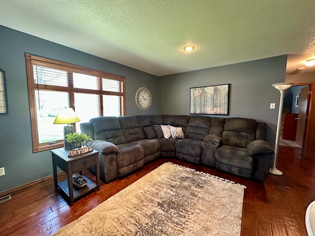 living area featuring dark wood-style flooring, a textured ceiling, visible vents, and baseboards