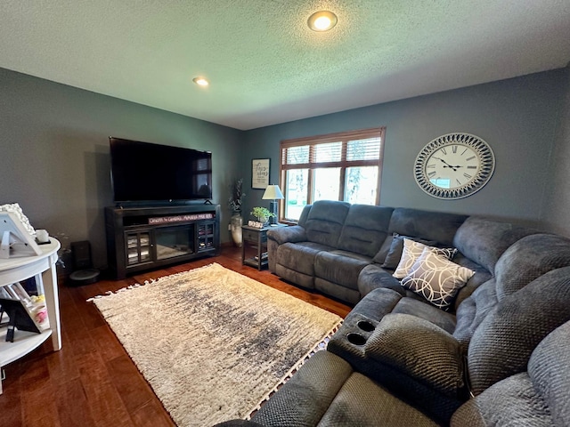 living room featuring dark wood-style flooring, a textured ceiling, and recessed lighting