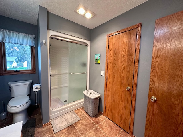 bathroom with toilet, tile patterned floors, a shower stall, and a textured ceiling