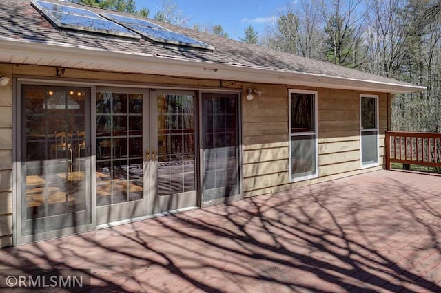 exterior space featuring roof with shingles and solar panels