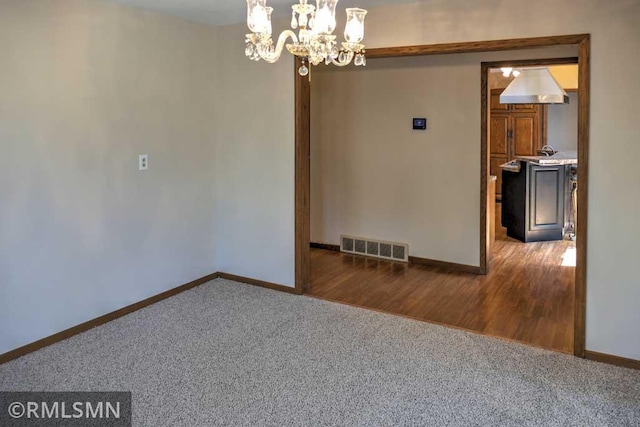 spare room with baseboards, carpet floors, a chandelier, and visible vents
