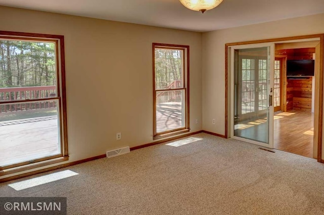 unfurnished room featuring visible vents, plenty of natural light, and carpet